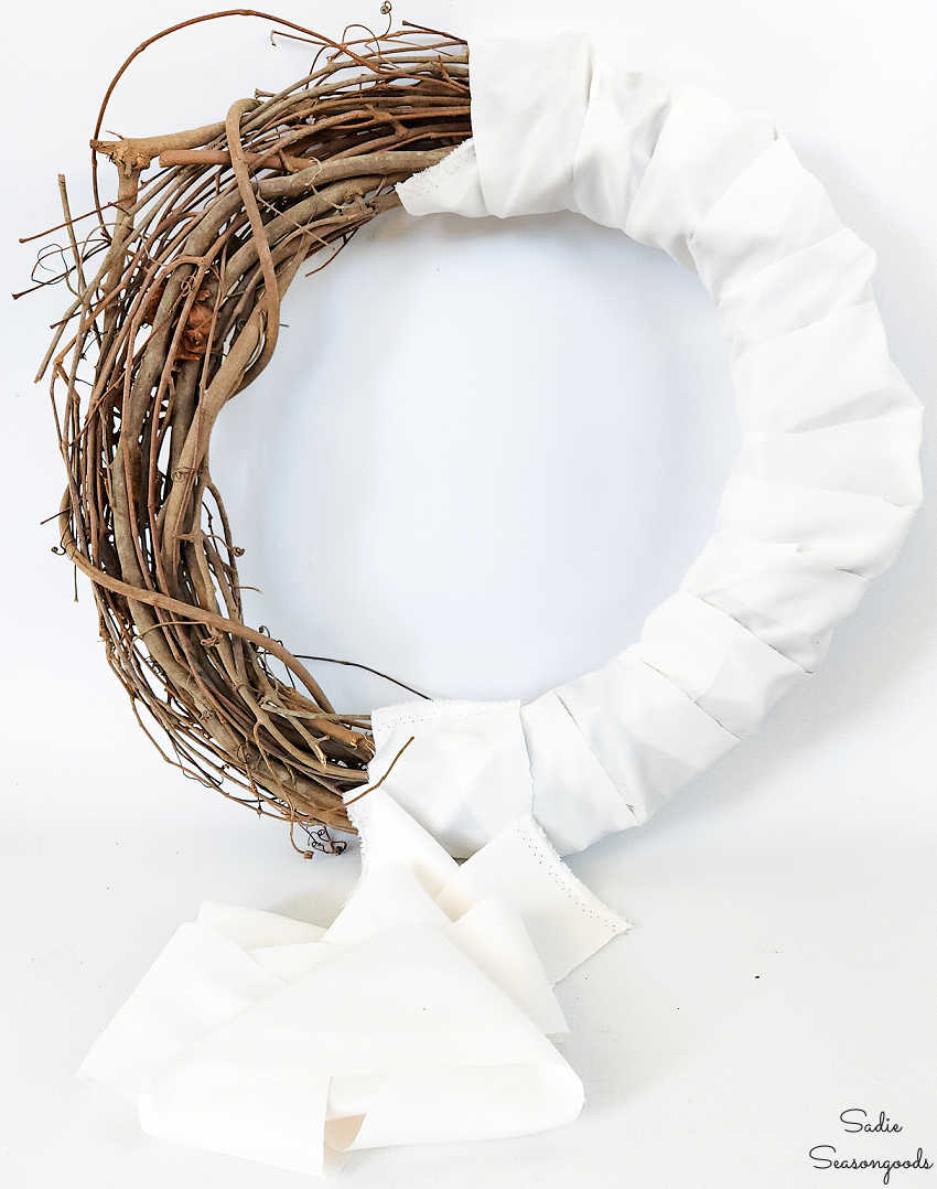 covering a grapevine wreath with fabric before wrapping it with a winter scarf